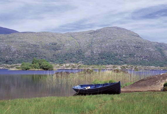 A rowing boat on a lake shore with mountains behind