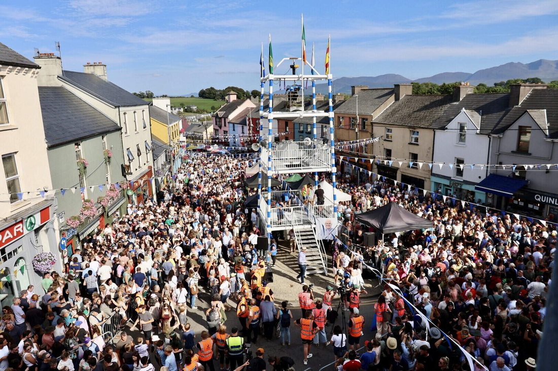 Crowds fill Killorglin's square around King Puck's tower at Puck Fair, with the Kerry mountains behind