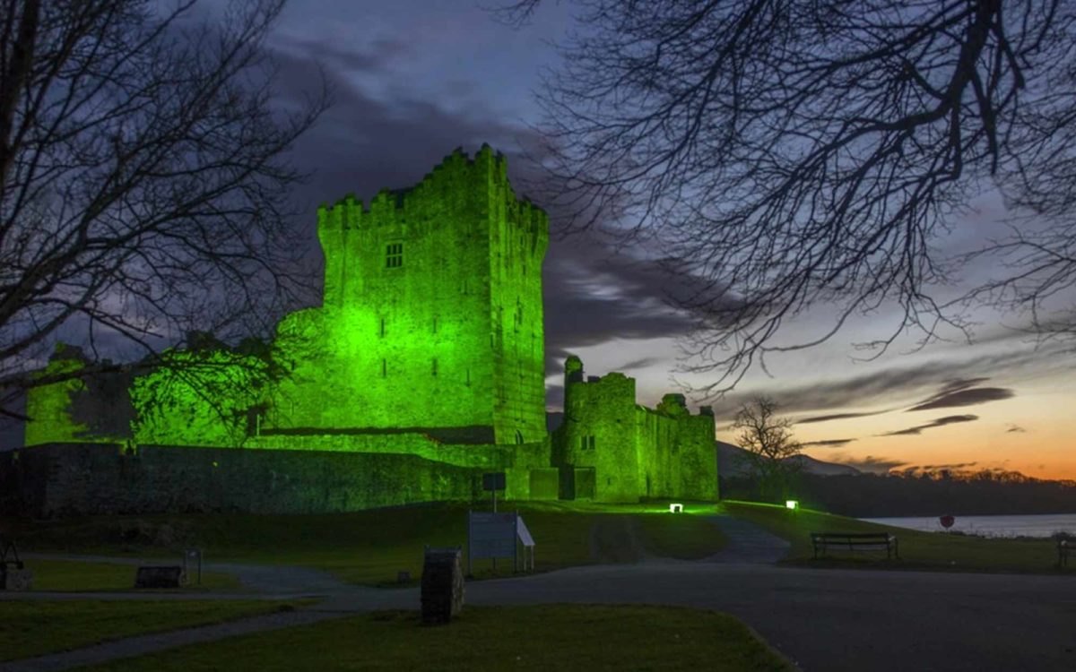 Ross Castle illuminated in green at dusk