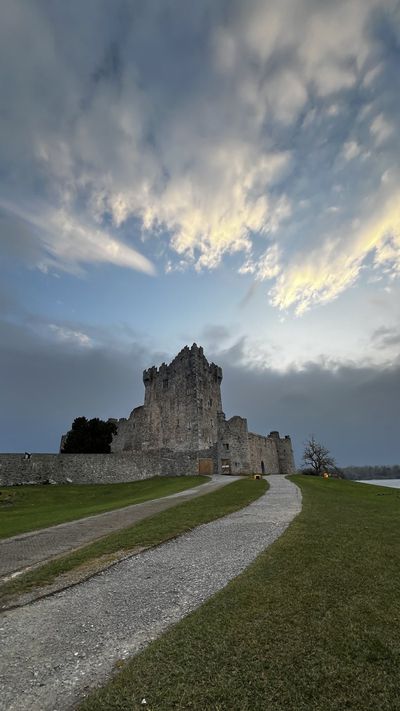 Ross Castle at the end of a gravel path under a dramatic sky