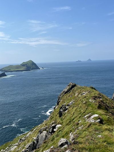 A grassy clifftop above the sea, with islands on the horizon