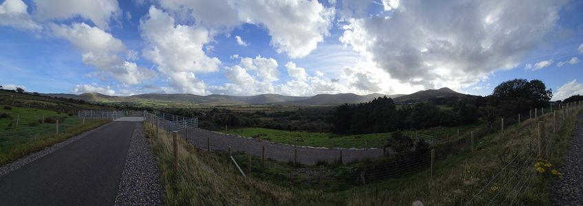 The Greenway path running past fields and fences towards the mountains under a cloudy sky