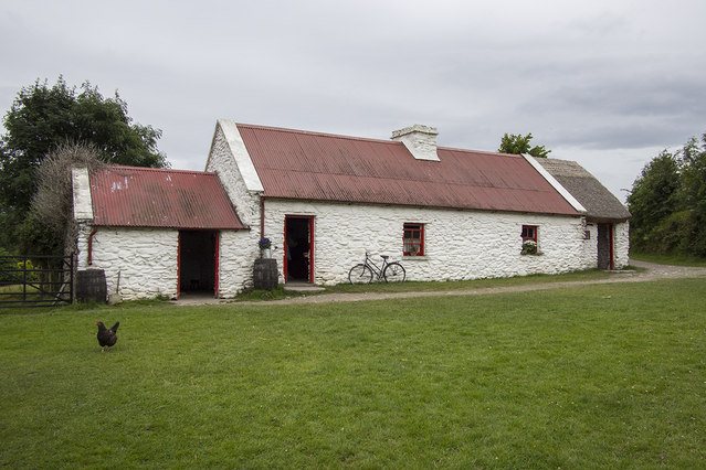 A whitewashed farmhouse with a red roof at Muckross Traditional Farms