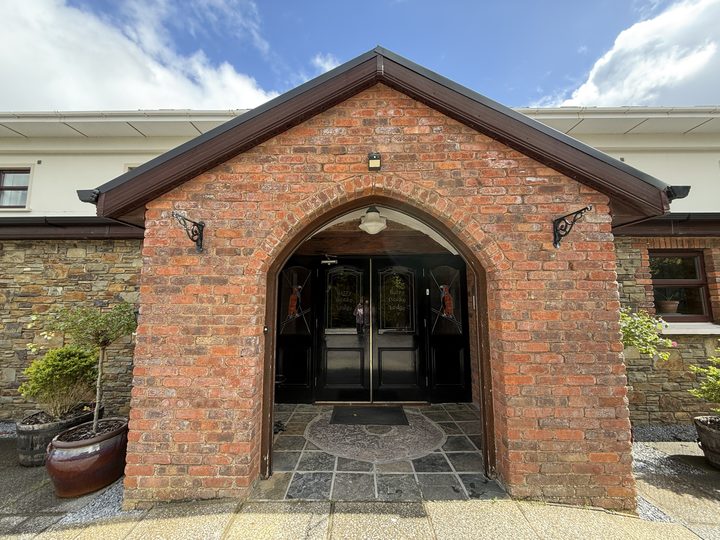 The red-brick entrance porch with its arched doorway and potted plants