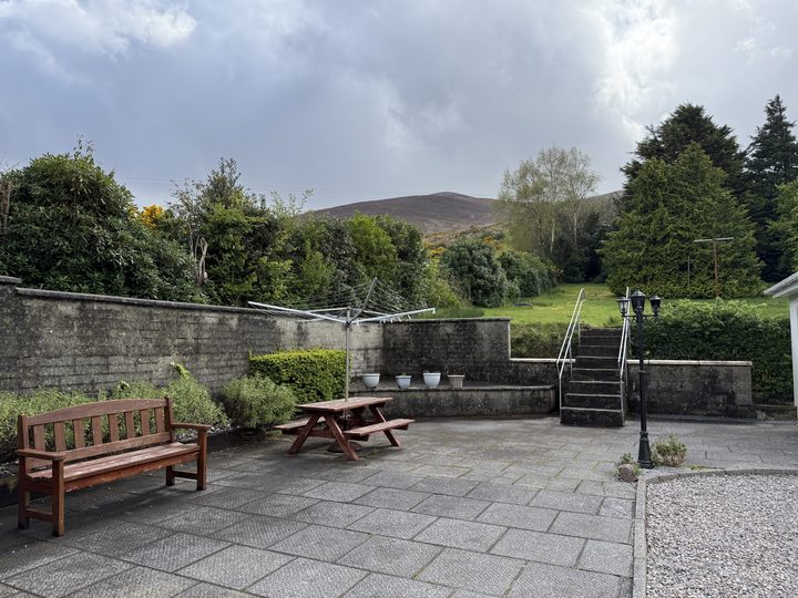 The paved patio with a bench and picnic table, and steps up to the garden