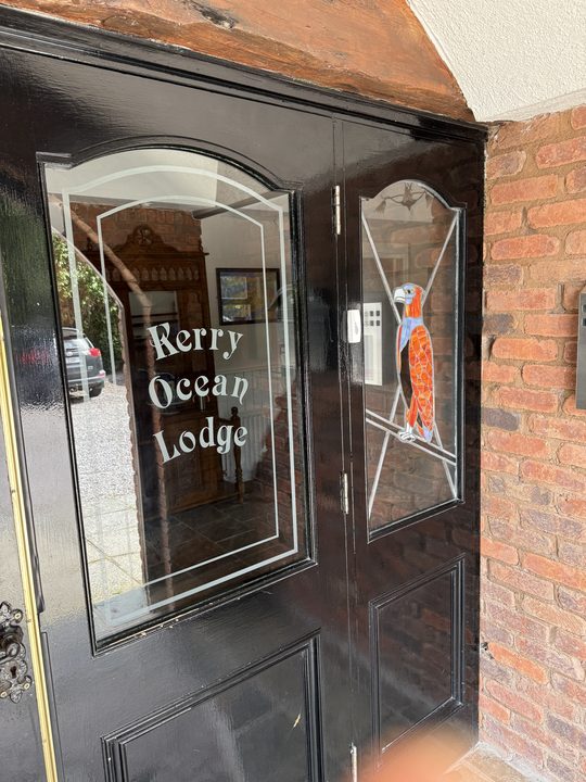 The black front doors with etched glass reading Kerry Ocean Lodge